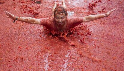 Un asistente a la Tomatina se tira en plancha sobre los tomates