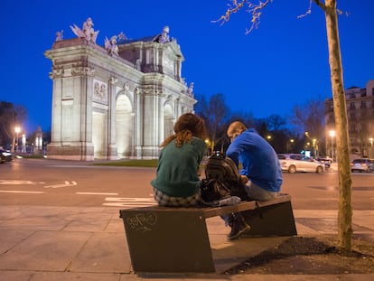 Dos jóvenes sentados en un banco cercano a la Puerta de Alcalá (Madrid) el pasado sábado.