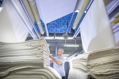 Worker using finishing machinery in textile mill