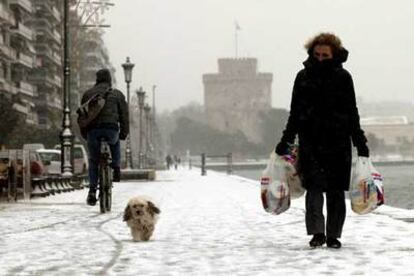 Viandantes de la ciudad portuaria griega de Salónica, tras la nevada de ayer.