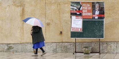 Una mujer pasa frente a unos carteles electorales del PSOE en Villalcazar de Sirga (Palencia).