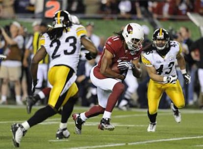 Larry Fitzgerald, de los Arizona Cardinals, se zafa de Tyrone Carter y Troy Polamalu en un momento del partido.