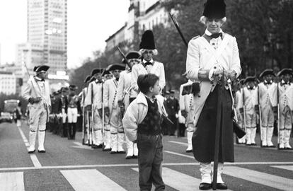 Un niño junto a uno de los soldados vestidos con uniformes de época en la calle de Bailén y Mayor, en el desfile con motivo del Dos de Mayo en 1990 en el que participaron varias bandas de música, que interpretaron conocidas marchas, con predominio de tambores y clarines.