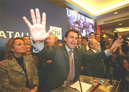 Artur Mas, entre su esposa y Jordi Pujol, saluda a sus seguidores con un gesto de euforia.
