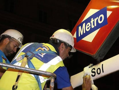 Workers replacing signage at Sol Metro station.
