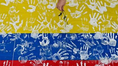 <span ><span >Un hombre deja un ramo sobre una bandera de Colombia. Foto: Luís Robayo (AFP /Reuters)</span>