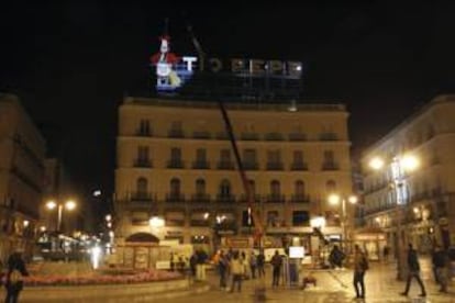 Los operarios empiezan a colocar el emblemático cartel luminoso de Tío Pepe que coronará el número 11 de la madrileña Puerta del Sol, tres años después de su retirada en abril de 2011.