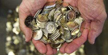 Un hombre sostiene varias monedas de euro.