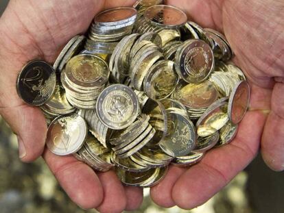 Un hombre sostiene varias monedas de euro.