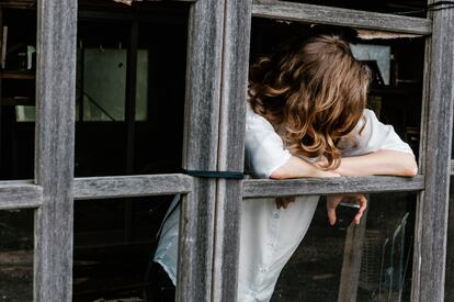 Una mujer reflexiona mientras mira por la ventana.