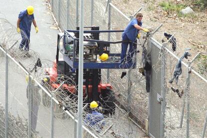 Un grupo de operarios españoles arregla los desperfectos de la valla tras el asalto de Ceuta. España tiene previsto colocar infrarrojos en todo el perímetro fronterizo con Marruecos y elevar la altura de los muros.