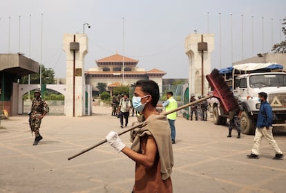 Un hombre camina este miércoles con una escoba frente al Parlamento nepalí, en Katmandú, durante el toque de queda.