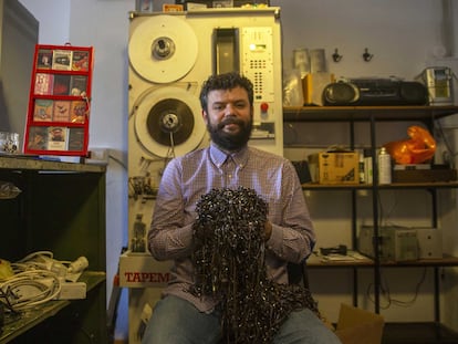 Luis, el dueño de la tienda La Cassetería posa con restos de cintas en su tienda en Madrid.