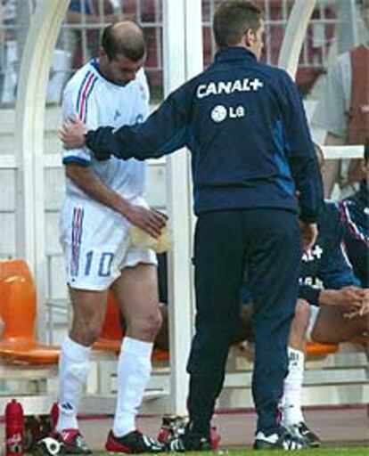 Zidane es atendido por un técnico de la selección francesa tras retirarse al banquillo.