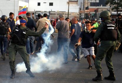 Um militar joga uma lata de gás lacrimogêneo que havia sido lançada do interior da base aérea da Carlota, nesta terça-feira em Caracas.