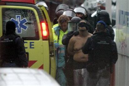 Uno de los terroristas detenidos en La Haya es conducido semidesnudo a un vehículo policial.
