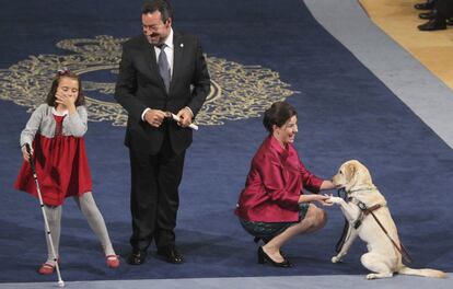 El presidente de la Organización Nacional de Ciegos Españoles (ONCE), Miguel Carballeda, acompañado por Liv Parlee Cantin (i) y Cristina Lucchese Seda y su perra guia Breezy, tras recoger de manos del Príncipe Felipe, y en presencia de la Princesa Letizia, el premio Príncipe de Asturias de la Concordia 2013.