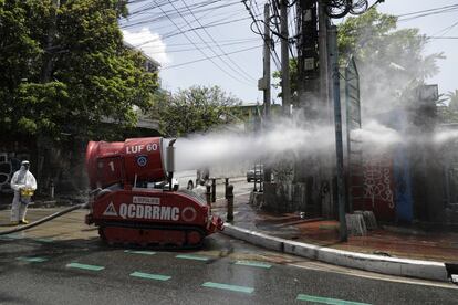 Una máquina operada por un trabajador con traje protector lanza líquido desinfectante en una calle de Manila, en Filipinas, este jueves.