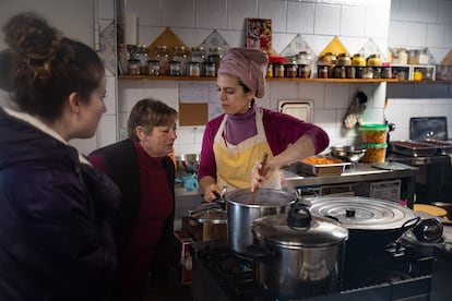 Maite López enseña la comida que está cocinando para la comunidad hinduista a Rosa Campesino y Esther Martín, naturales de Brandilanes.