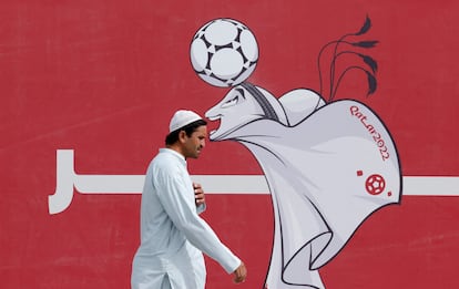 A man walks past a poster of the Qatar 2022 mascot La'eeb in Doha.