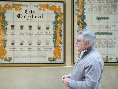 El propietario del Café Central de Málaga, Rafel Prado, junto al mítico azulejo del establecimiento con las nueve formas de pedir un café.