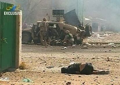 Un hombre yace en el suelo tras la explosión de los coches bomba, y a unos metros, soldados de EE UU atienden a otros heridos.
