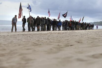 El llamado Día D supuso el desembarco de decenas de miles de fuerzas en cinco playas distintas de Normandía. En la imagen, un grupo de personas camina en la playa de Omaha con banderas de los países aliados, en Normandía (Francia).
