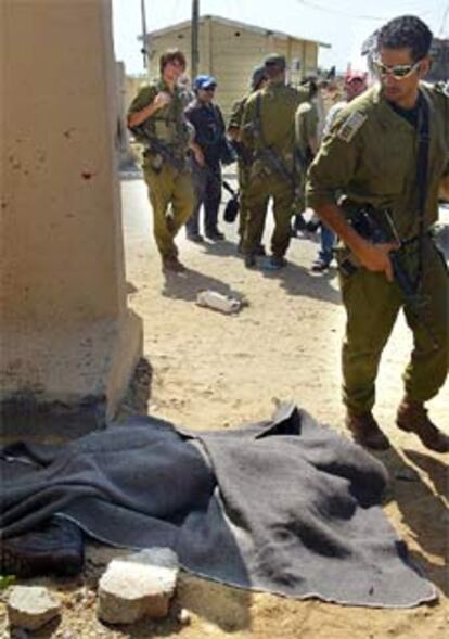 Un soldado israelí, ante uno de los cuerpos cubierto por una manta cerca de Erez.