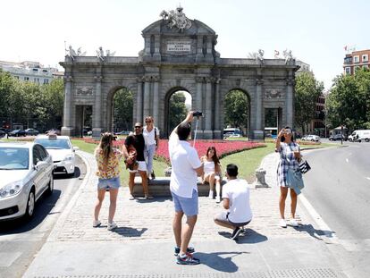 Varios turistas se fotografían ante Puerta de Alcalá, en el centro de Madrid.
