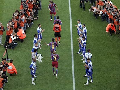 Los jugadores del Espanyol hacen pasillo a los del Barça en homenaje al campeón antes del inicio del partido.
