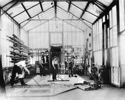 Georges Méliès pintando un decorado en el suelo de su estudio en Montreuil, con un dibujo preparatorio en una de las manos.