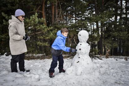 Un niño, junto a su madre, se divierte haciendo un muñeco de nieve en la estación de esquí de La Molina (Girona). Se esperan heladas en los sistemas montañosos de la mitad norte y del sudeste, y, aisladamente, en páramos, más intensas en los Pirineos; y sin grandes cambios en los archipiélagos.