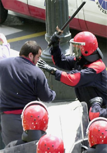 Un agente amenaza con su porra a uno de los manifestantes.