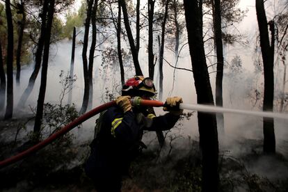 Un bombero lucha contra el fuego en la zona de Kryoneri, al norte de Atenas, el jueves.