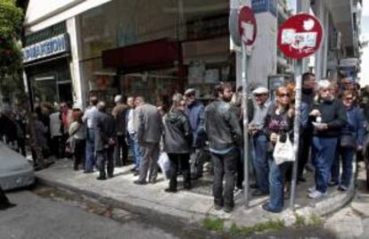 Varias personas hacen cola delante de una farmacia abierta en la zona Pagrati, en Atenas (Grecia) hoy, viernes 28 de marzo de 2014.