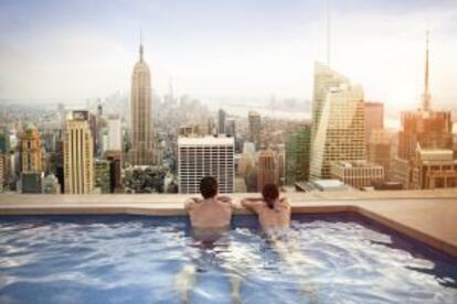 Dos personas miran el 'skyline' de Manhattan desde la piscina de un hotel.