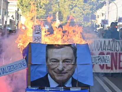 Estudiantes prenden fuego a un póster del primer ministro italiano, Mario Draghi, durante una protesta en Turín convocada con motivo de la jornada de huelga general que vive el país.