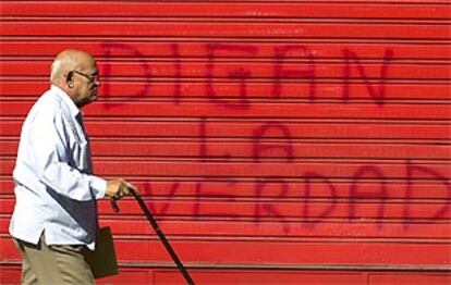 Un hombre pasa junto a un cartel pintado por los manifestantes chavistas en una puerta de <i>El Nacional.</i>