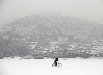 Un hombre monta una bicicleta durante las nevadas en Kabul (Afganistán). Más de 26.000 niños han muerto o han quedado mutilados como consecuencia de la guerra en Afganistán durante los últimos 14 años, lo que supone una media de cinco niños fallecidos o heridos cada día en ese periodo, según un informe de Save the Children.