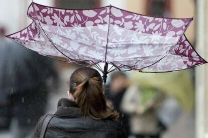 Una mujer intenta protegerse de la lluvia y el viento en Sevilla.