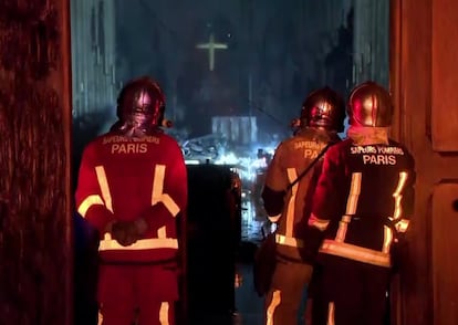 Miembros de la brigada de bomberos de París, en una entrada de la catedral de Notre Dame, la noche de lunes al martes.