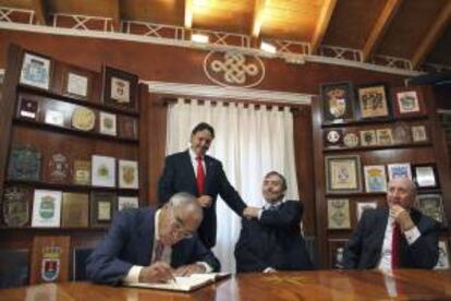 El presidente de Endesa, Rodolfo Martín Villa (i), acompañado por el alcalde de Brañosera, Jesús Mediavilla (2i), el expresidente del senado Juan José Laborda y el arquitecto y dibujante, José María Pérez "Peridis", firma el libro de honor del ayuntamiento de la localidad de palentina de Brañosera.