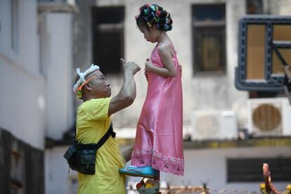 Los habitantes desfilaron con estatuas de deidades por las callejuelas del pueblo y la plaga terminó. En la foto, un hombre hace un gesto a una niña de cuatro años vestida como la casera de la película de Stephen Chow "Kung Fu Hustle".