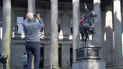 Un hombre fotografía la estatua del duque de Wellington coronado con un cono de tráfico, en Glasgow en agosto de 2023.