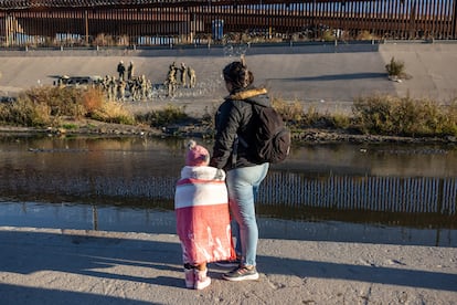 Una migrante y su hija observan a militares estadounidenses desde el lado mexicano de la frontera, en Ciudad Juárez.