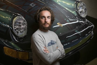 Manu Campa, pintor realista, fotografiado delante de una de sus pinturas de un Porsche.