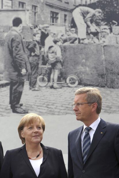 La canciller alemana, Angela Merkel, y el presidente, Christian Wulff, junto al monumento conmemorativo que han inaugurado, donde se ve la construcción del Muro hace 50 años