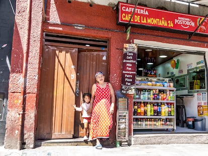 Una mujer de la tercera edad junto a su nieta afuera de una cafetería en Bogotá.