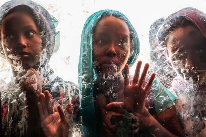 Niñas refugiadas eritras, desplazadas recientemente debido al conflicto en la región de Afar, observan tras un cristal en el recinto del Hotel Agda, en la ciudad de Semera, Etiopía, el 14 de febrero de 2022. Miles de refugiados eritreos, conmocionados y separados de sus seres queridos, huyeron a través de terrenos difíciles para escapar de la artillería y de los disparos.