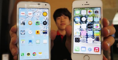 Un empleado de Samsung muestra los modelos Galaxy 5 y el iPhone 5.